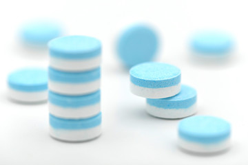 Round plain compress tablets with blue and white layer.