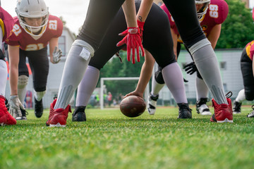 Photo of american football players with ball on the playing field on summer day