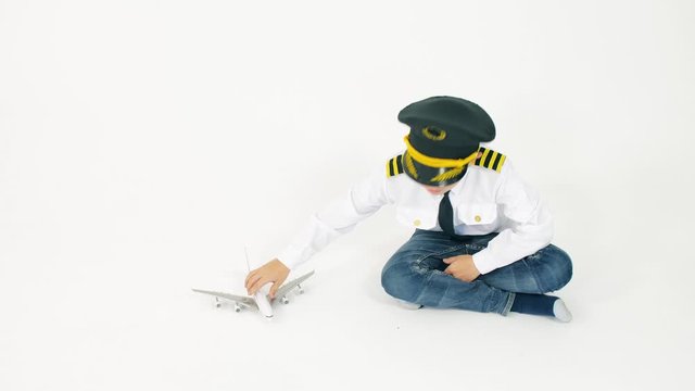 Boy wearing pilot's uniform plays with toy commercial airplane. Aircraft landing