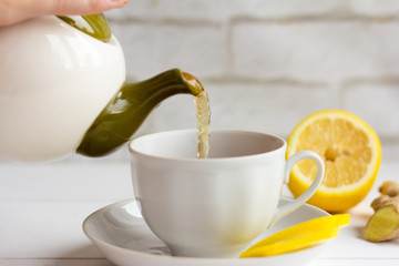 Close-up of pouring tea into a white Cup.Tea with lemon and ginger.