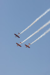 Three colorful jets flying in the sky and performing a show leaving smoke marks