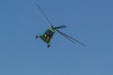 A military bright green helicopter flying in the blue sky