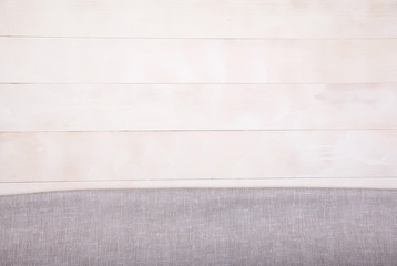 Linen light gray tablecloth lies on a white wooden background. Horizontally. View from above. Copy spaes.