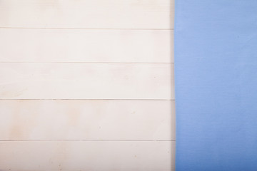 A blue cotton tablecloth lies flat on a white wooden background. Horizontally