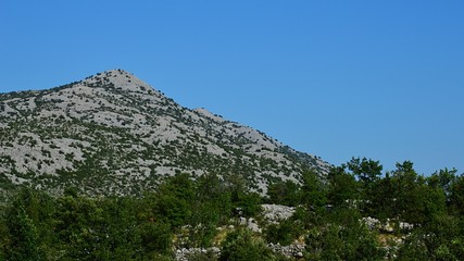 Rocky hill of Velebit mountain with some vegetation during hot summer day. Location near Paklenica national park, Croatia, 