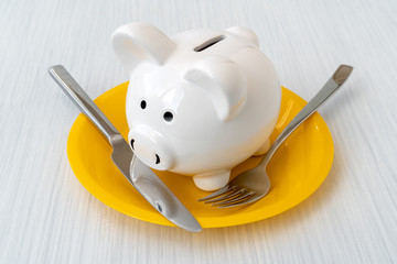 Piggy bank with a fork and knife on the plate