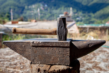 Rusty black blacksmith anvil and a hammer