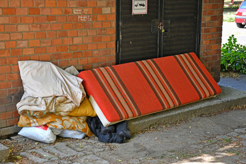 Bed of homeless people next to a brick wall