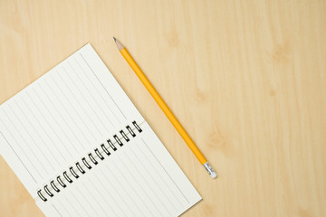 yellow pencil with notebook on wooden desk,flat lay. Top view.