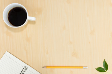 Top view of notebook pencil and cup of coffee on wood table background.Business desk minimal style concept with copy space for any design.Flat lay.