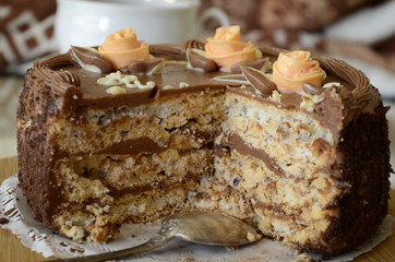 Cake with nuts and meringues decorated with cream rose. Shallow depth of field, close-up.
