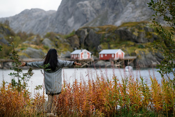 Asian woman with black hair happy with scenic view of lofoten islands in Norway