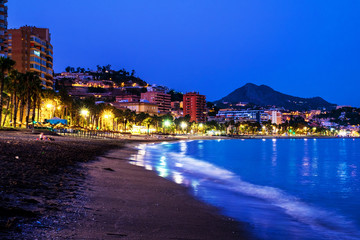 Famous Malagueta beach in Malaga, Spain at night. Coastline and motion blurred waves at sunset