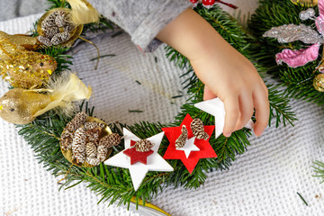 Hands of a child decorate Christmas Advent wreath from fir twigs