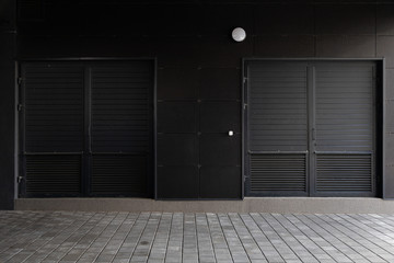 Two black corrugated doors - service entrance of building