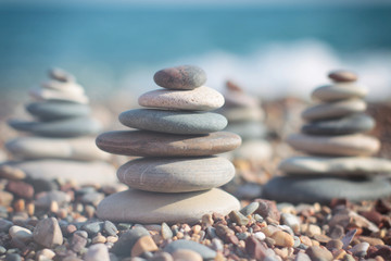 Zen pyramid of spa stones on the blurred sea background. Sand on a beach. Sea shores. Place for text.