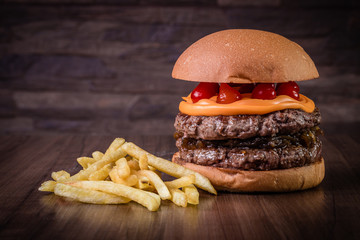 Double craft beef burger with cheddar cheese, caramelized onion.and pepper pout on wood table and rustic background.