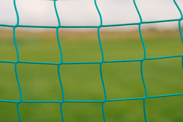 Soccer football net background wallpaper over green grass and blurry stadium behind