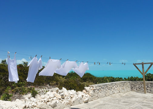 White shirts dry on a clothesline next to the Caribbean Sea in the Turks and Caicos islands