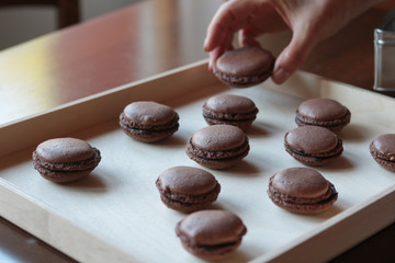 chocolate macarons arranged on a wooden tray