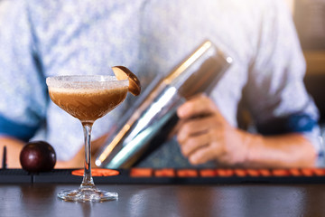 Bartender making delicious cocktails in the bar. (high ISO and shallow dept of focus image)