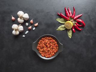 Red hot sauce, garlic, red pepper and spices on a black table. Top view. 