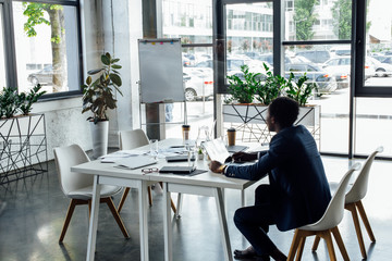 african american businessman sitting at table and using laptop