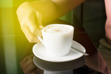 cup of coffee on a table with woman hand
