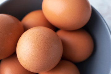 Close-up raw brown organic eggs, top view. Macro chicken eggs in gray bowl, farm product