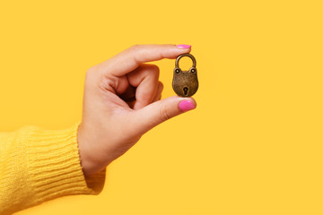bronze lock in hand over yellow background