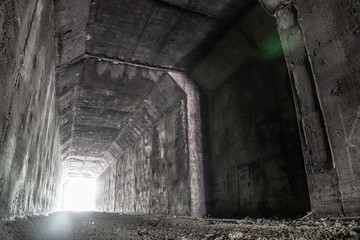 Empty abandoned dark tunnel with light in the end.