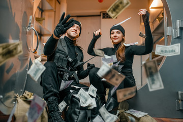 Fototapeta na wymiar Happy robbers throwing money at the vault