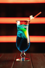Fresh blue cocktail on a neon background. Alcoholic cocktail. Fruit Non-alcoholic cocktail.