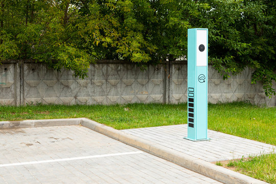 Battery charging area for modern electrocars against fence and green trees