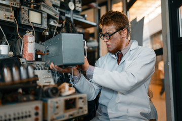 Naklejka na ściany i meble Scientist in glasses holds electrical device