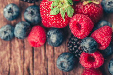 Fresh Summer Berries mix with Strawberry, Raspberry, Red currant, Blueberry and Blackberry on wood background.