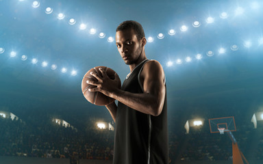 Young professional african american basketball player with a ball on a floodlit court