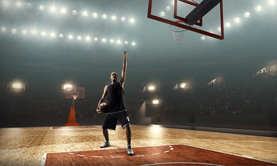 Basketball player on a crowded and floodlit basketball arena celebrates victory