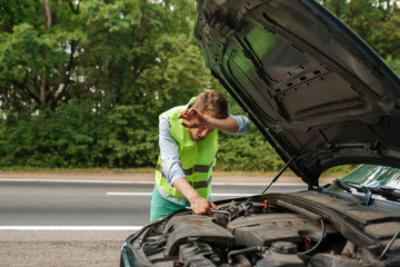 Tired man at opened hood fix problem with engine