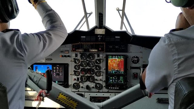 Two pilots in white shirts in the cockpit fly a passenger plane. View from behind.