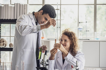 Team of Medical Research Scientist Conducts Experiments in Laboratory with Microscope, Test Tubes, Micropipette and other equipment.