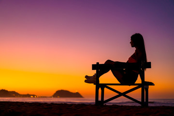 Fototapeta na wymiar Zarautz, Gipuzkoa / Spain »; September 2019: Lifestyle, a girl sitting on a chair in summer sunset