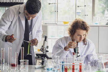 Team of Medical Research Scientist Conducts Experiments in Laboratory with Microscope, Test Tubes, Micropipette and other equipment.