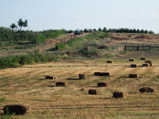 Obraz premium Tractor works on a field with hay