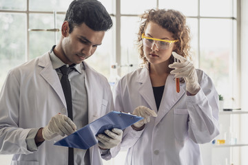 Team of Medical Research Scientist Conducts Experiments in Laboratory with Microscope, Test Tubes, Micropipette and other equipment.