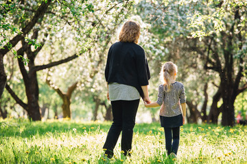 Fototapeta premium Mother and daughter having fun in the park. Happiness and harmony in family life. Beauty nature scene with family outdoor lifestyle. Woman and cheerful little girl