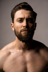 Fototapeta premium Handsome man in spectacles, portrait. Bearded guy without shirt. Strong eye contact.