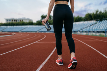 Female runner, back view, training on stadium