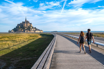 A couple heads to Mont Saint Michael on the only access road. On foot it is one of the options allowed for access, perhaps the most beautiful because it is enjoying a spectacular landscape.