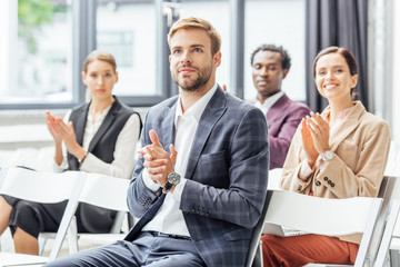 selective focus of businessman in formal wear clapping during conference